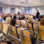 ludzie na konferencji oraz przemawiający pawel schmidt